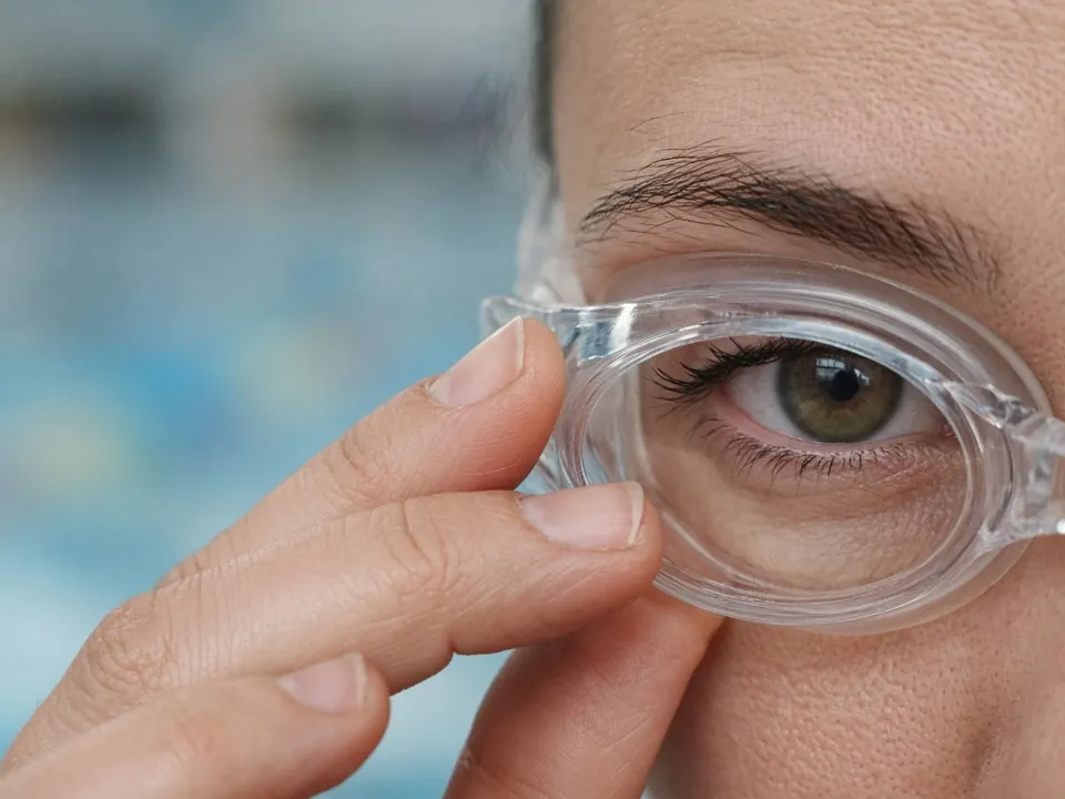 Schwimmbrille wird ohne Band an die Augenpartie gehalten, Nahaufnahme